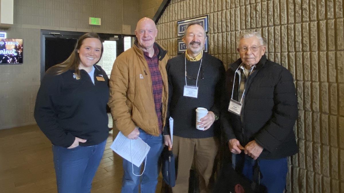 A group of three men and a woman pose for the camera.